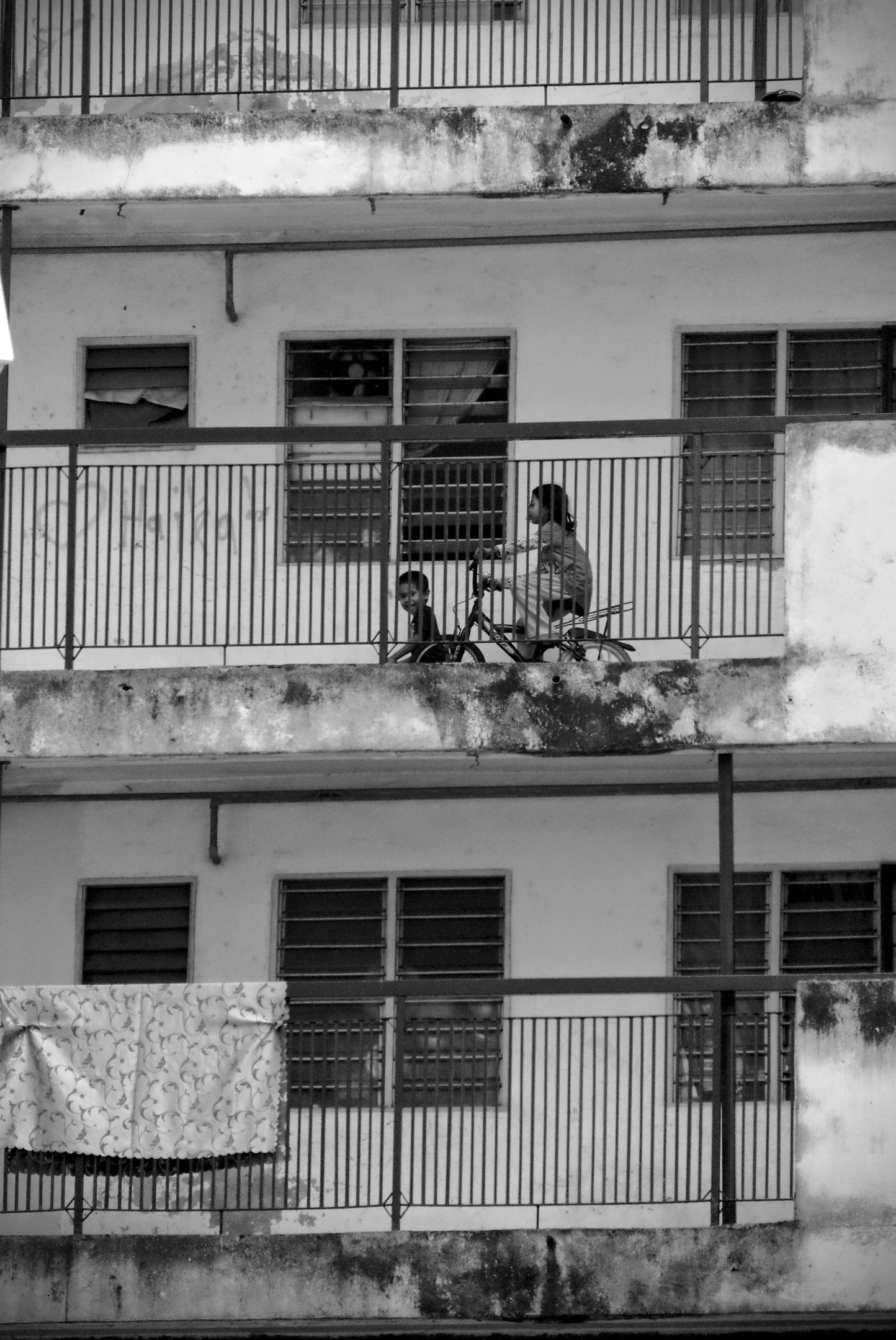 Malaysian children playing and riding bicycles in high rise public housing walkways, Kota Damansara PPR